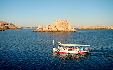 A boat sailing past Philae Temple Island in Aswan, Egypt